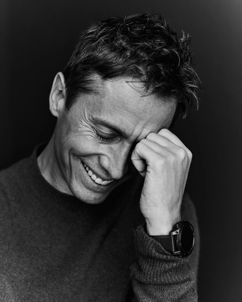 Black and white actor headshot of a man with a relaxed emotional expression against a dark background.