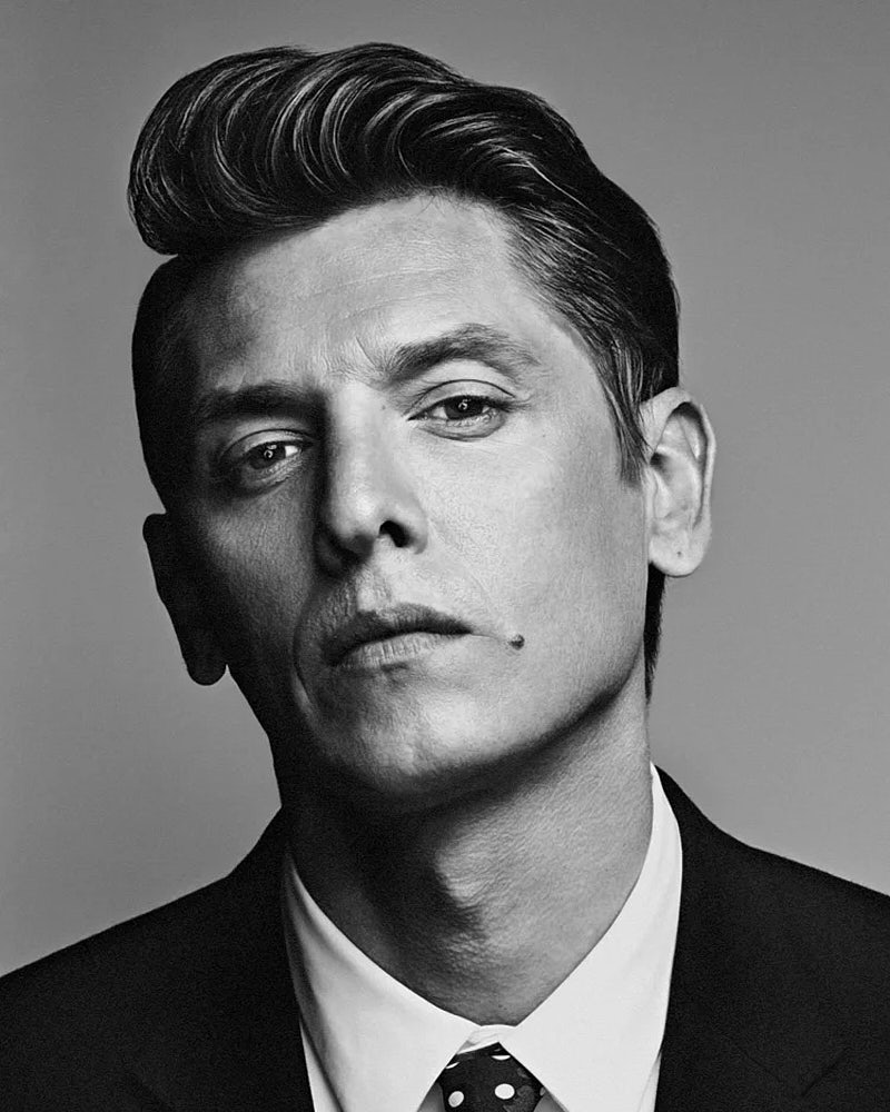 Dramatic black and white studio portrait of a man in a suit.
