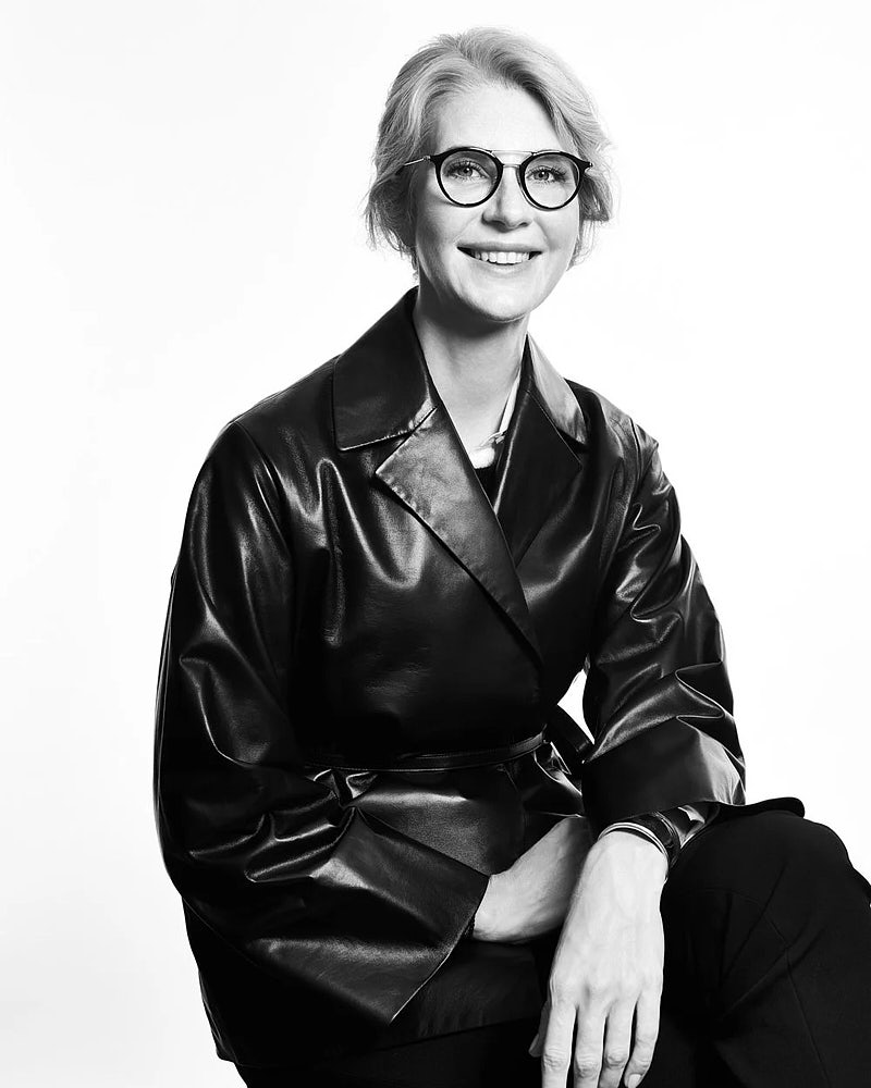 Editorial business portrait of a woman in glasses and a leather jacket.