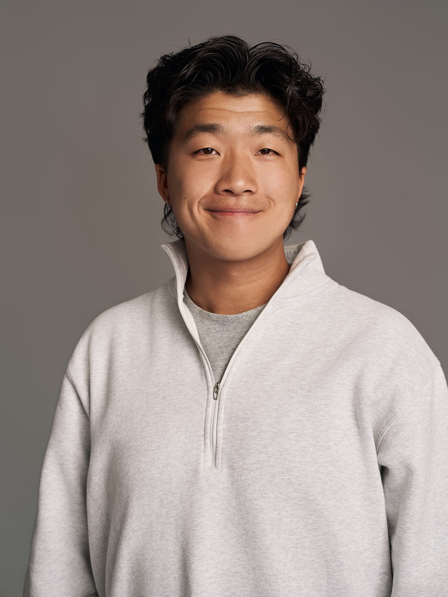 LinkedIn headshot of a man in a light sweater photographed on a neutral gray background.