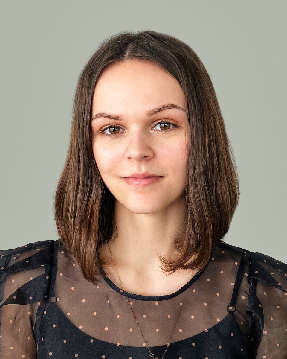 Remote headshot of a young woman in a black blouse photographed against a muted green background.