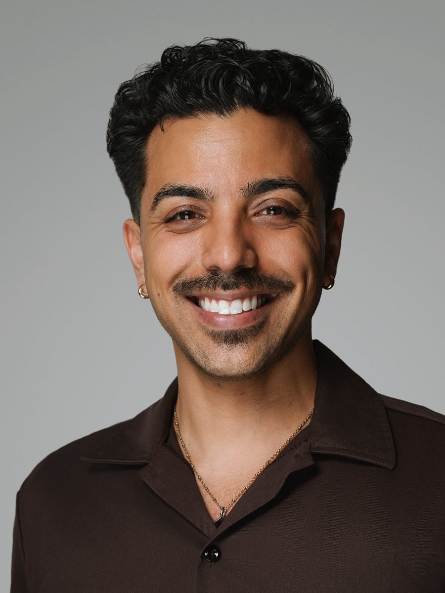 Clean studio headshot of a man in a brown shirt against a neutral background.