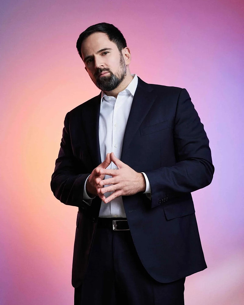 Business team portrait of a man in a suit photographed on a pink and blue gradient studio background.