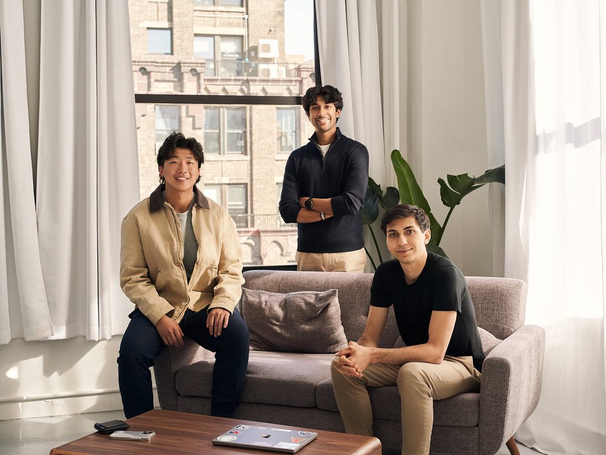 Team portrait of three professionals photographed together in a bright office setting.
