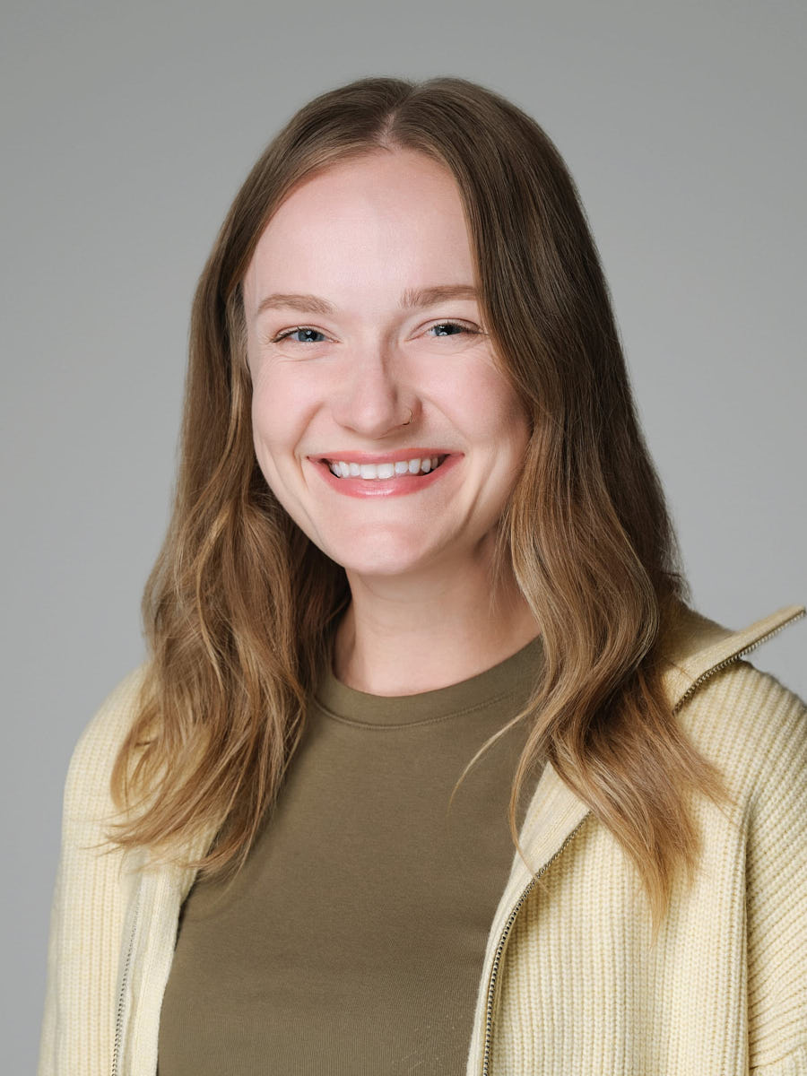 Approachable team headshot of a smiling woman photographed against a neutral light background.